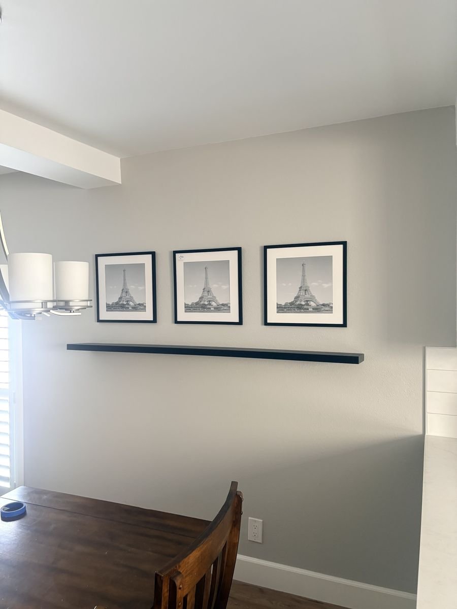 Three framed prints evenly spaced above a floating shelf