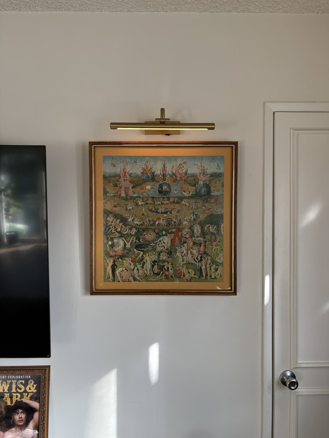 Framed art with picture light mounted on wall