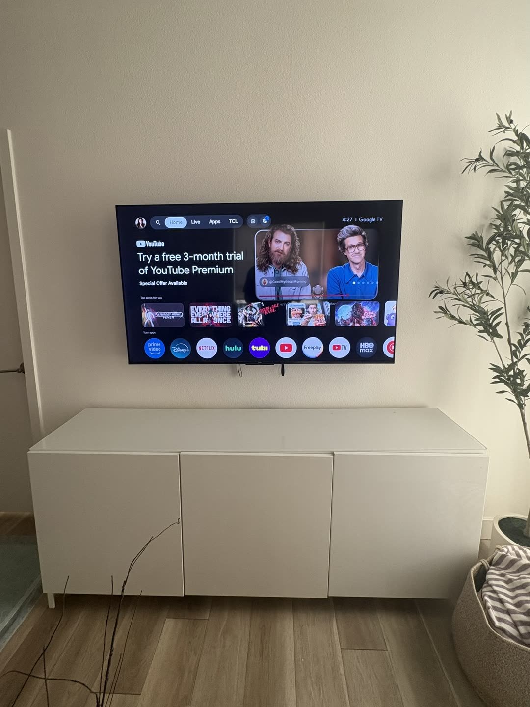 TCL TV mounted above white cabinet