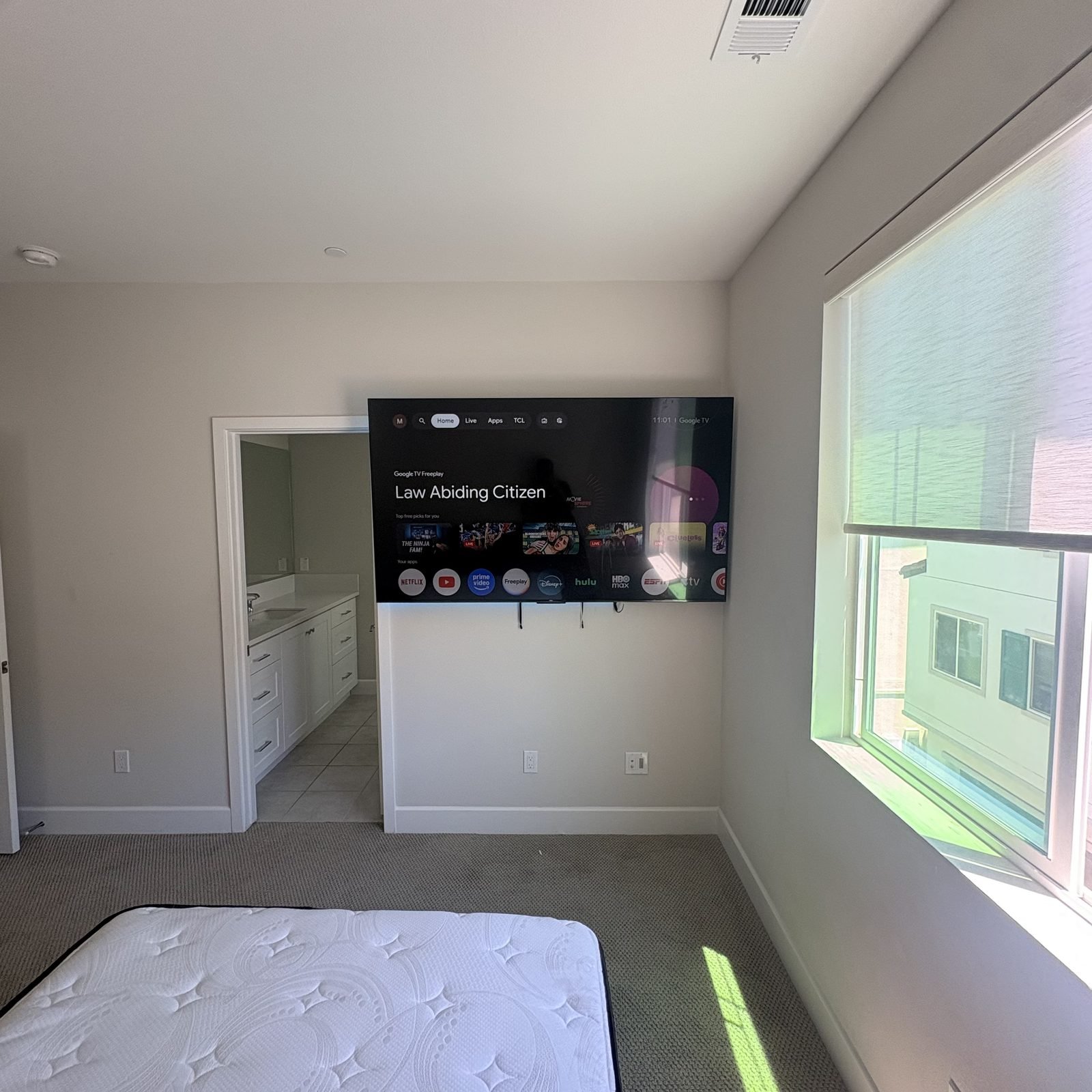 Large TV mounted in primary bedroom with ensuite bathroom