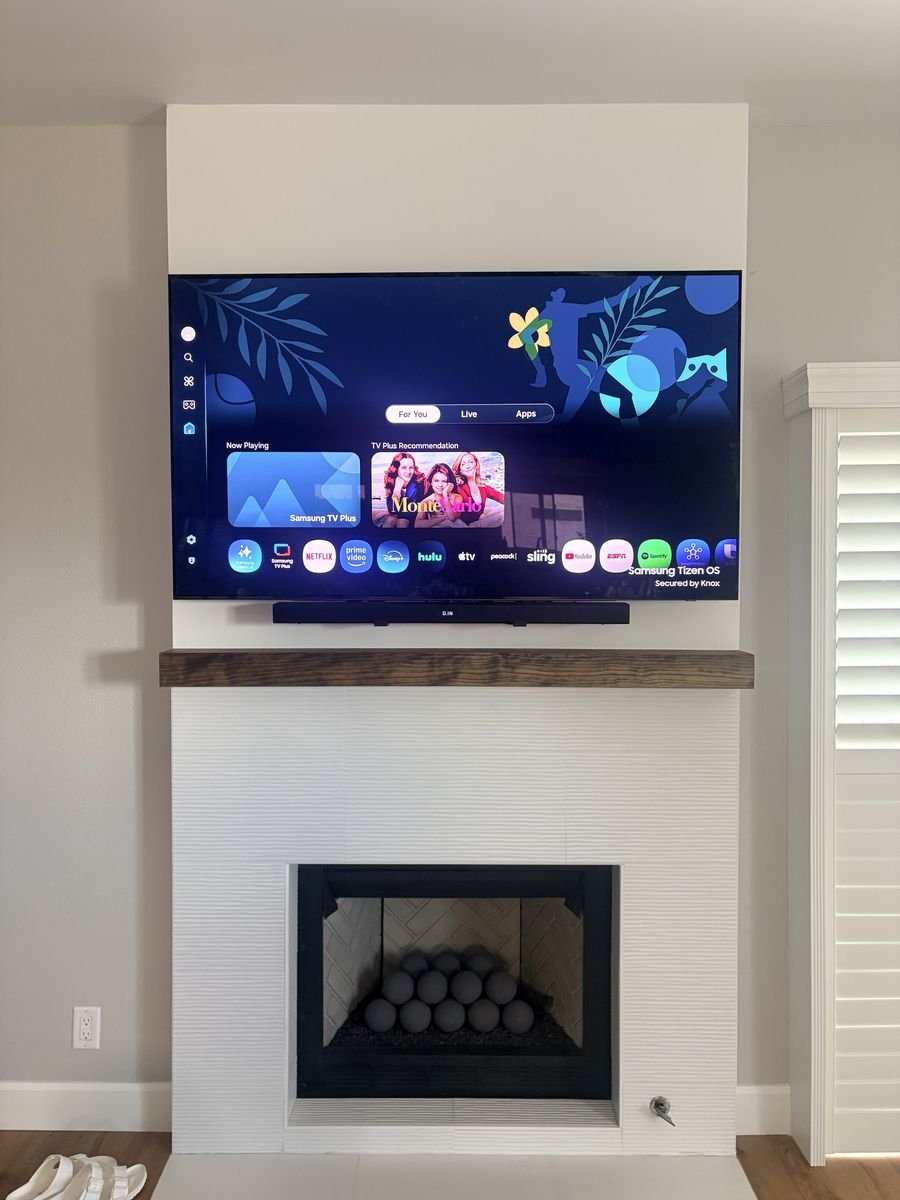 Samsung TV with a soundbar mounted directly below it above a fireplace mantel