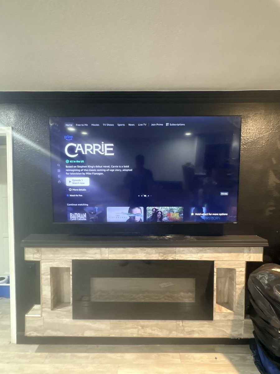 TV mounted above a tiled fireplace and dark mantel in a Los Angeles home