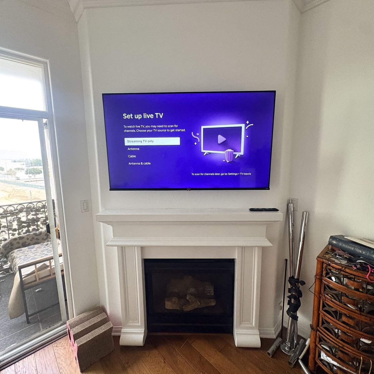TV mounted above a white fireplace mantel in a corner living room